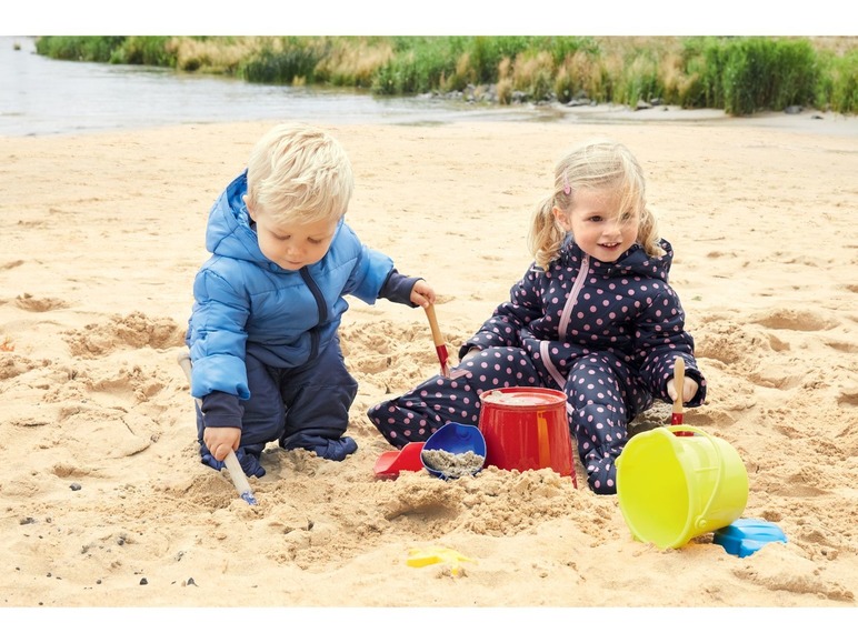 Zwei Kinder spielen mit Schaufeln und Eimern im Sand.