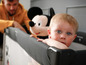 Ein Baby in einem Kinderbett mit einem Mickey Mouse Plüschtier.