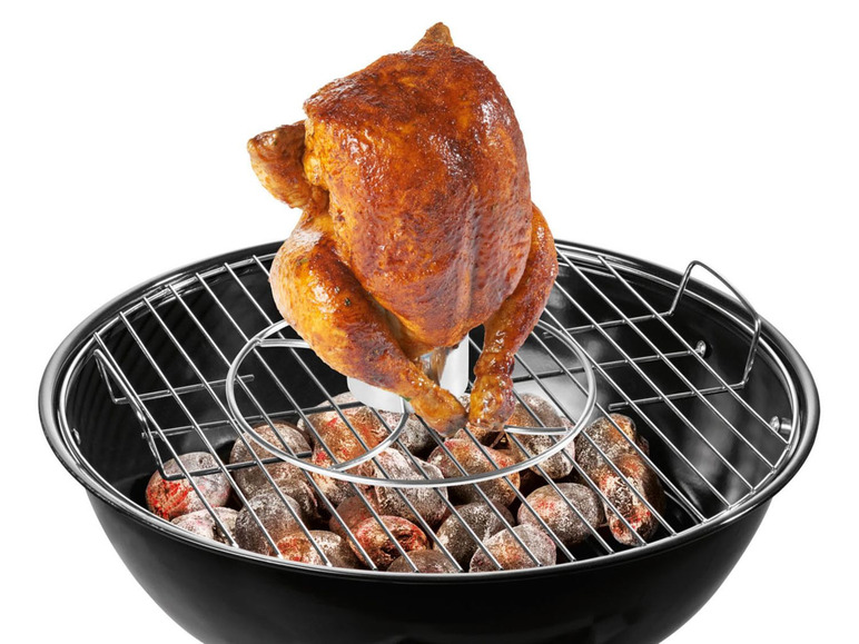 Ein Brathähnchen über Kohlen in einem schwarzen Grill.