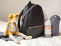 Eine schwarze Rucksack, ein Schnullerbehälter und eine graue Wickeltasche für Babys.
