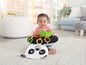Baby sitzt auf einem Panda-förmigen Sitzkissen mit Spielzeug.