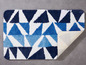 Badteppich mit geometrischem Muster in Blau und Weiß.