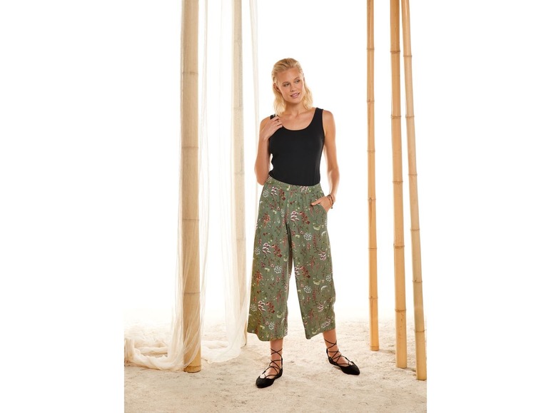 Frau in schwarzem Top und grünen Hosen mit Blumenmuster