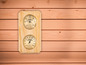 Ein Sauna-Thermometer und ein Hygrometer an einer Holzwand.