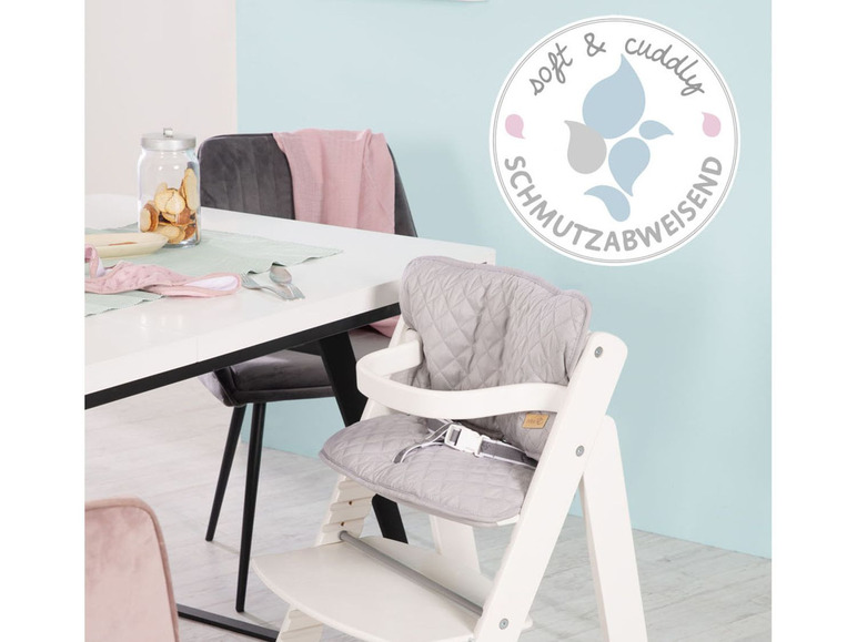 Ein weißer Hochstuhl mit einem grauen, gepolsterten Sitz.