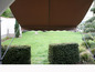 Ein beiges Sonnensegel über einem grünen Garten.