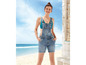 Eine Frau trägt eine Jeans-Overall-Shorts am Strand.