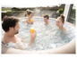 Eine Familie genießt ein Whirlpool-Bad im Freien mit Getränken.