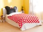 Ein Bett mit roter Bettwäsche mit weißen Punkten und einem Mickey Mouse Kopfkissen.