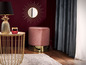 Ein rosa Samt-Hocker, ein goldener Couchtisch und ein Sonnenspiegel.