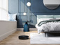 Ein Roboterstaubsauger in einem modernen Schlafzimmer mit Bett und Beistelltisch.