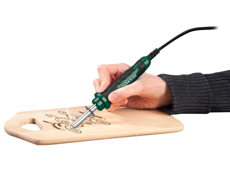 Eine Hand, die einen Parkside-Brennstift verwendet, um ein Holzbrett zu verzieren.