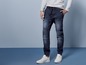 Mann in dunkelblauen Jeans mit weißen Sneakers.