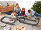 Eine Familie spielt mit einer Carrera-Rennbahn mit Autos.