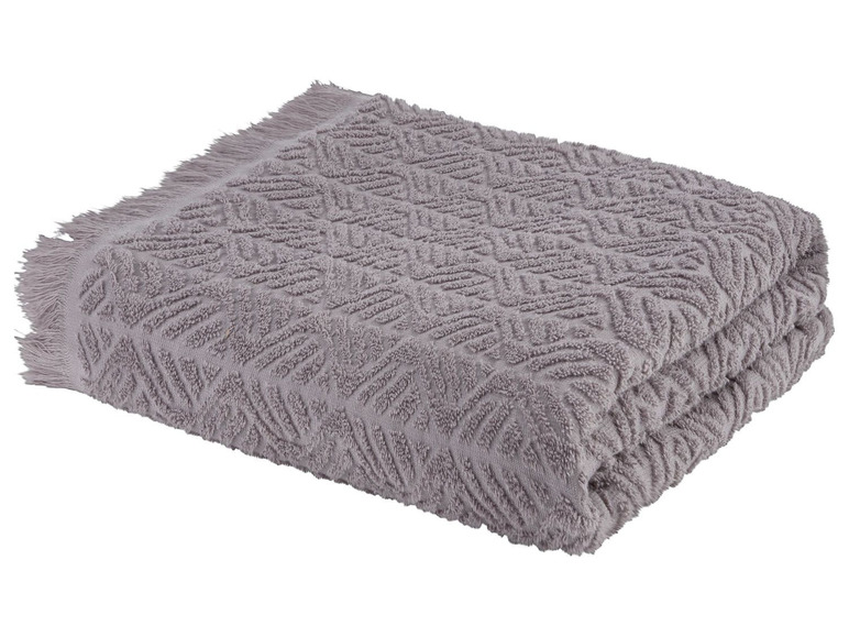 Ein graues Handtuch mit geometrischem Muster und Fransen.