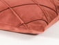 Ein terracottafarbenes Kissen mit Rautenmuster.