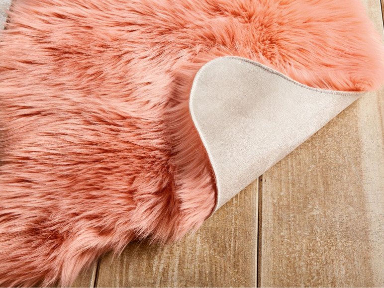 Ein rosa Plüschteppich mit beigefarbener Rückseite.