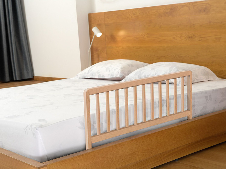 Ein Holzbett mit einem Schutzgitter.
