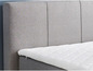 Ein graues Boxspringbett mit einem weißen Topper.