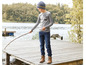 Ein Junge mit einem grauen Shirt, blauen Jeans und einer blauen Mütze steht auf einem Holzsteg am Wasser.