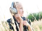 Eine junge Frau mit Bose-Kopfhörern in einem Grasfeld.