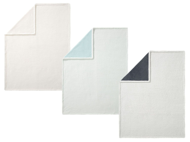 Drei weiche Decken in Weiß, Hellblau und Grau.