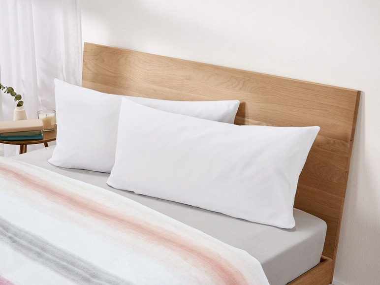 Weiße Kissen auf einem Bett mit gestreiftem Bettbezug.