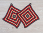Zwei gehäkelte Topflappen in grau, rot und beige.