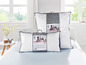 Zwei TrendLine Kissen in grauen und weißen Verpackungen auf einem Bett.