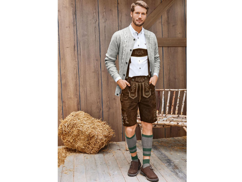 Mann in Lederhosen mit Strickjacke und Socken.