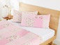 Rosa Bettwäsche mit Blumendruck und einem Patchwork-Kissen.