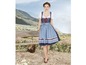 Eine Frau in einem blauen Dirndl mit weißer Bluse und roten Akzenten.
