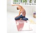 Eine Frau macht Yoga auf einer rosa Yogamatte mit Mandala-Muster.