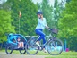 Eine Frau fährt Fahrrad mit einem Anhänger für zwei Kinder.