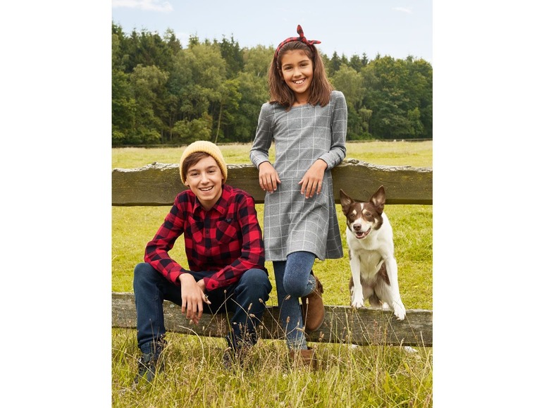 Ein Junge und ein Mädchen in lässiger Kleidung mit einem Hund.