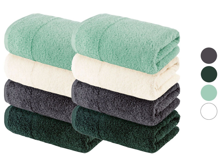 Stapel Handtücher in Mintgrün, Creme, Dunkelgrau und Dunkelgrün.