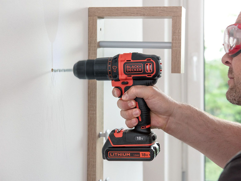 Ein Mann verwendet einen Black+Decker Akku-Bohrschrauber, um ein Regal an die Wand zu montieren.