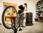 Ein Mann repariert ein Mountainbike in einer Garage mit Hilfe eines Werkstattwagens mit Aufbewahrungsboxen.