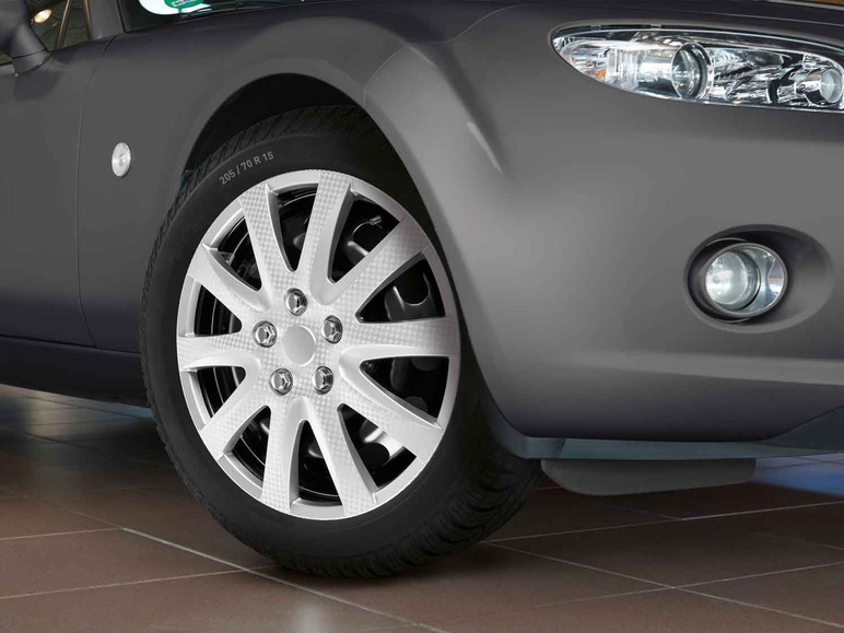 Nahaufnahme einer silbernen Radkappe an einem grauen Auto.