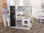 Ein Kind spielt mit einer Spielzeugküche mit Backofen, Waschmaschine und Kühlschrank.