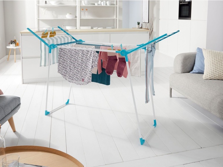 Ein weißer und blauer Wäscheständer mit Kleidung in einer Küche.