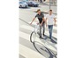 Zwei Männer gehen mit einem Fahrrad über einen Zebrastreifen.