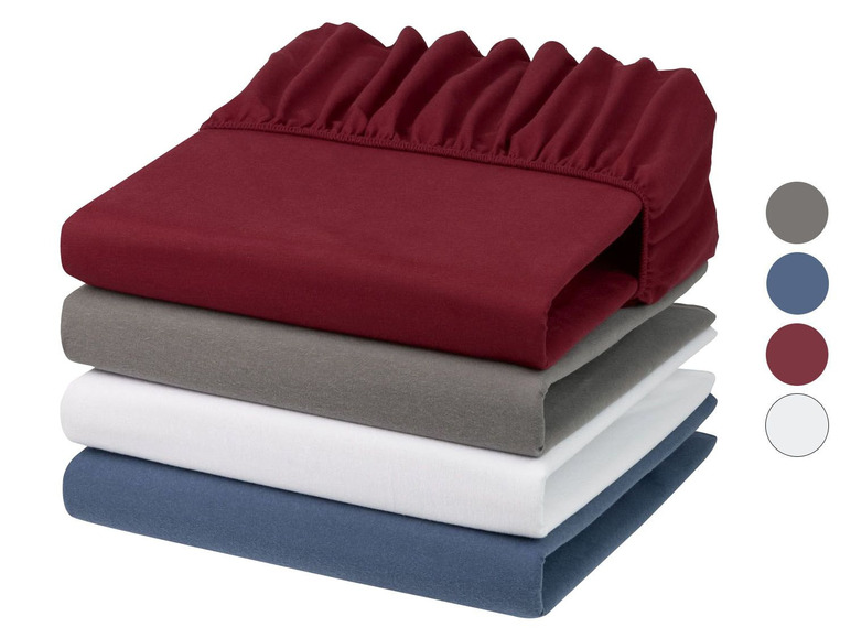 Ein Stapel Bettlaken in bordeaux, grau, weiß und blau.