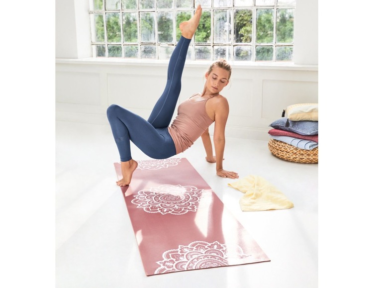 Frau macht Yoga auf einer rosafarbenen Yogamatte mit Mandala-Muster.