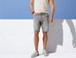 Mann in grauen Denim-Shorts und weißen Sneakern.