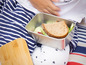 Eine Lunchbox aus Metall mit einem Sandwich und einem Holzbrett zum Schneiden.