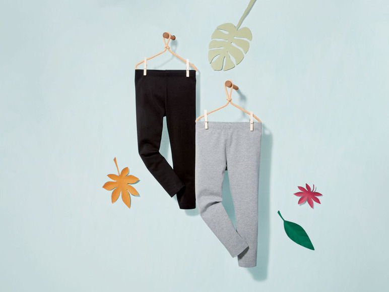 Schwarze und graue Leggings hängen an Kleiderbügeln