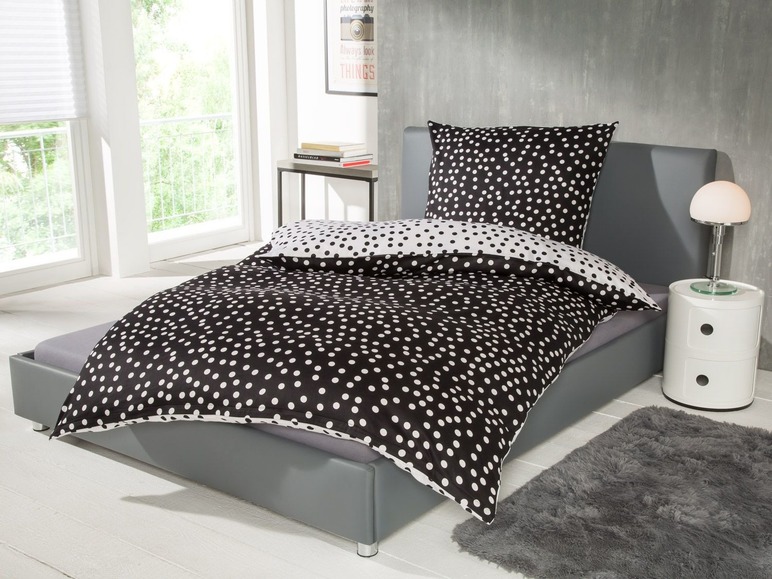 Bett mit schwarz-weißem Bettzeug mit Punkten.