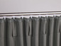 Grauer Vorhang mit weißen Clips an einer Metallstange.