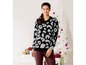 Eine Frau trägt einen schwarzen Pullover mit Leopardenmuster.